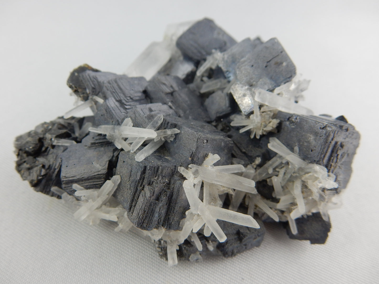 Blocky complete mass of galena crystals (Lead sulfide) with scattering of fine milky quartz needles