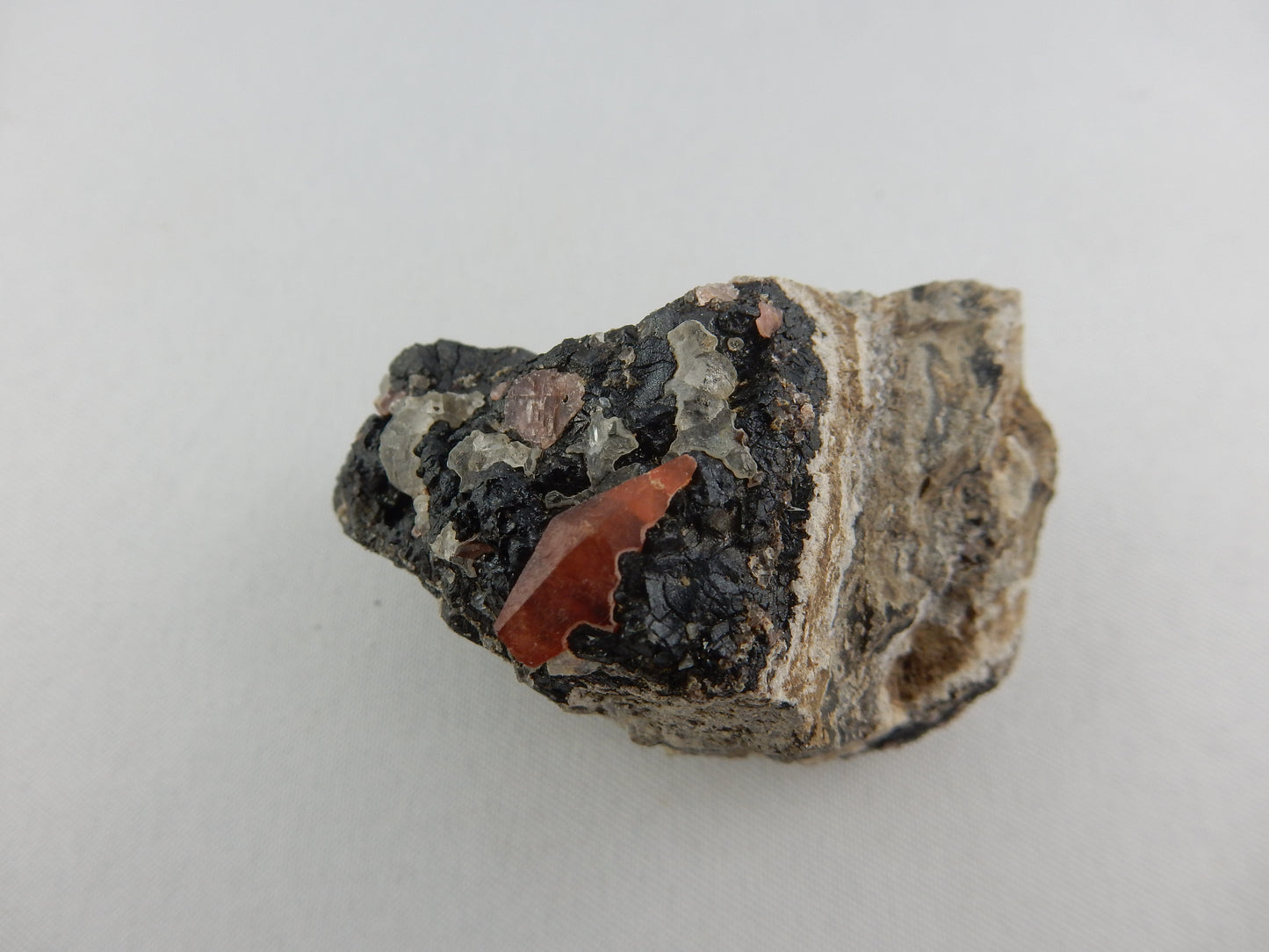 Complete double-terminated scalenohedron of ruby-red Rhodochrosite on interesting banded matrix of sulfides