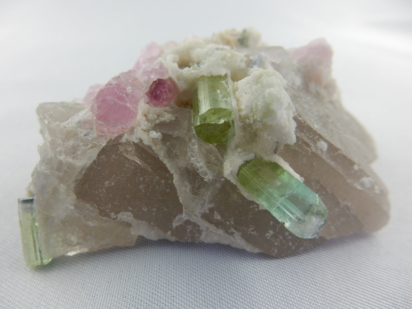 gemmy intense pink and contrasted green multiple and watermelon tourmalines - poised on a bed of quartz crystal