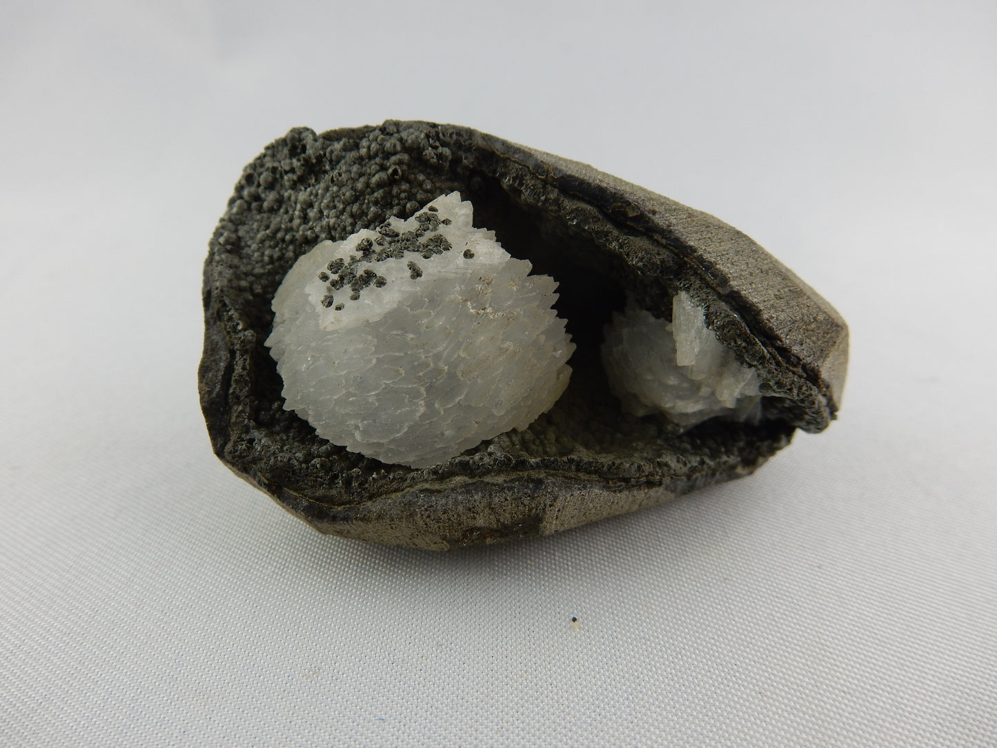 White gemmy stack of Heulandite nestled in a black calcite(?) and volcanic matrix vug