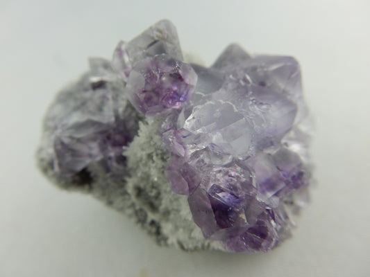 interesting cluster of two generations of light/clear cubes and darker purple phantom cubes on bed of drusy quartz