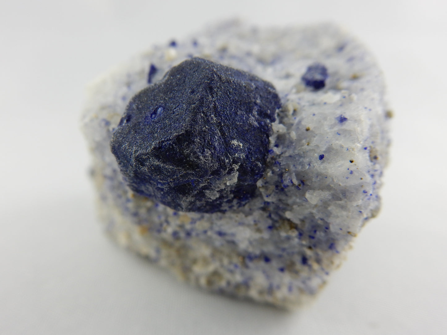 complete dodecahedron single Lazurite crystal perched on calcite and smaller lazurite, pryite and phlogopite