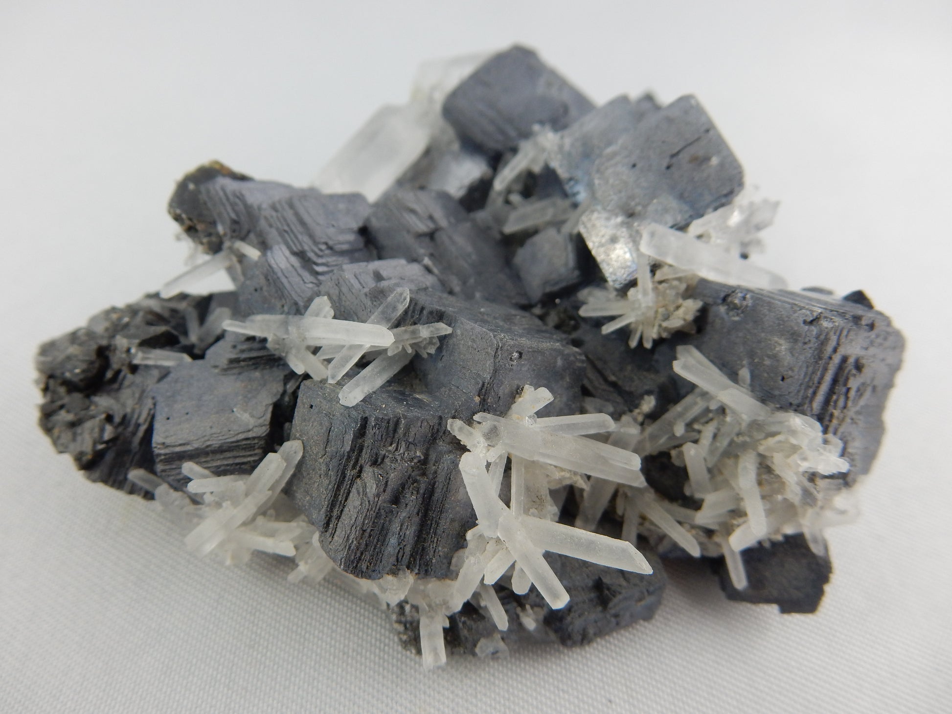 Blocky complete mass of galena crystals (Lead sulfide) with scattering of fine milky quartz needles