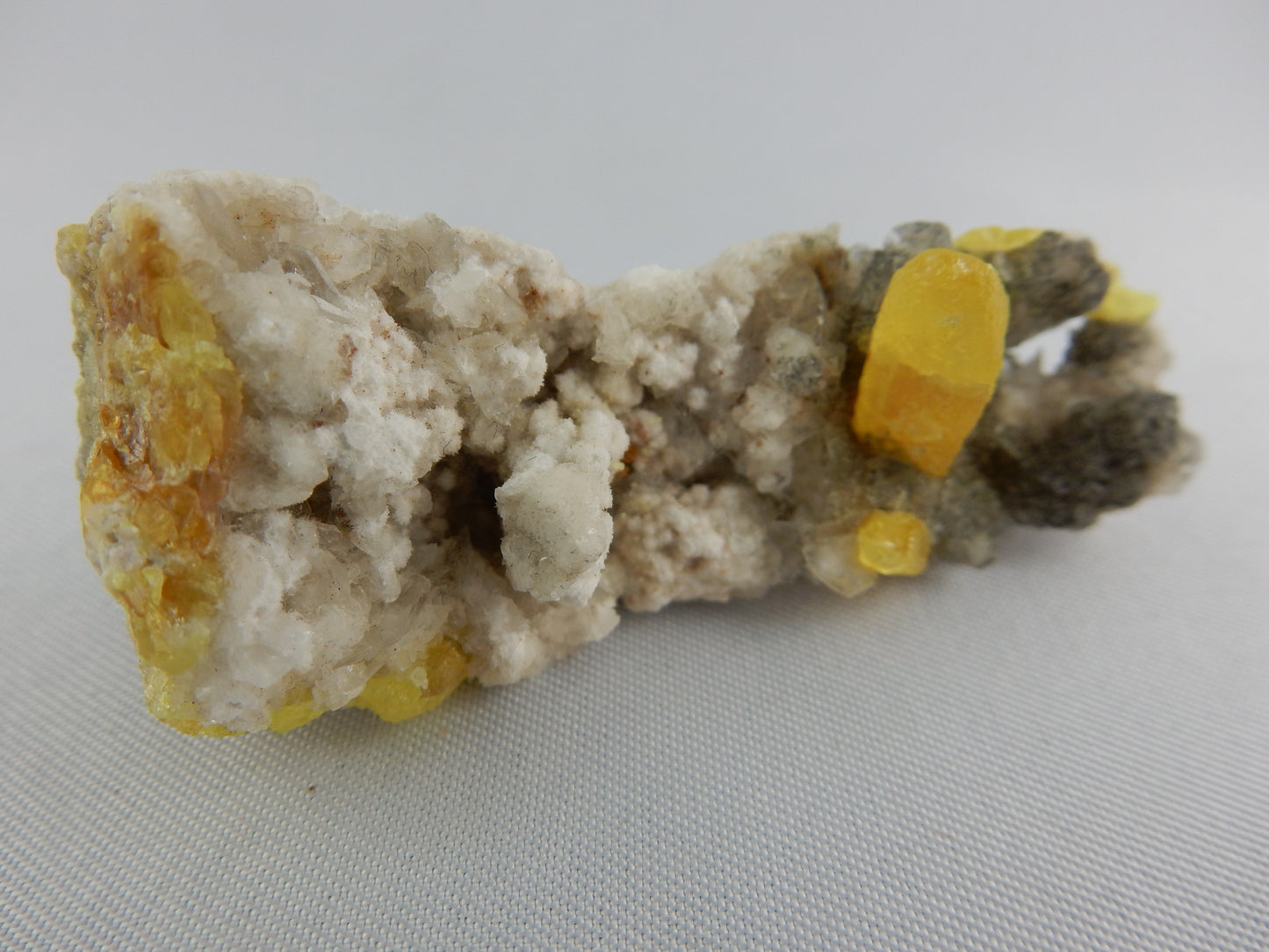 large single perfect scaledrahedron crystal of yellow sulfur plus several smaller crystals