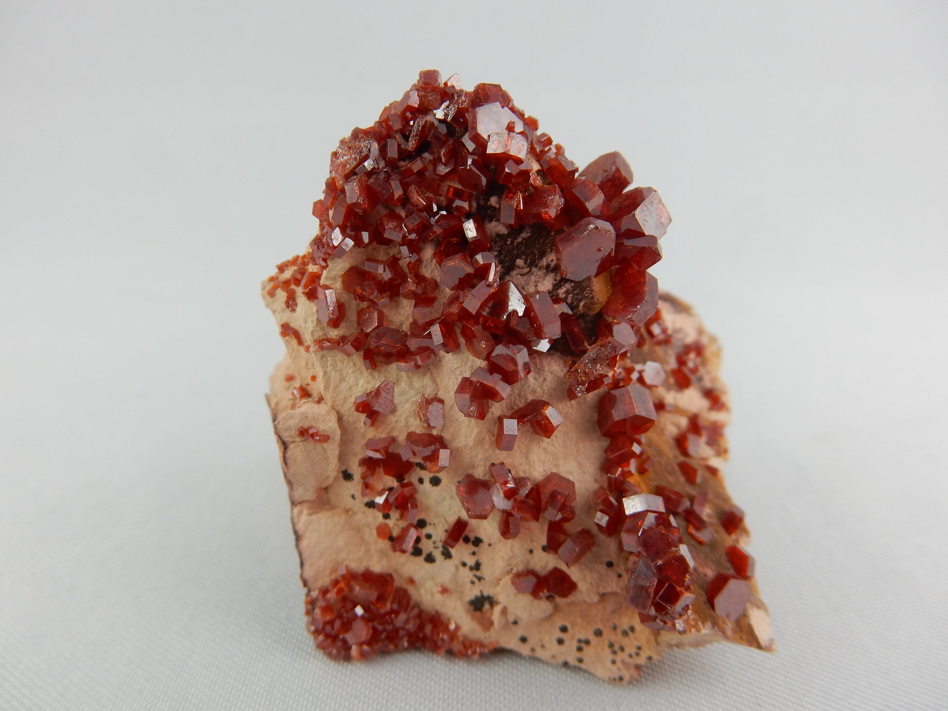 cherry red type of hexagonal "barrel-shape" very sparkly crystals scatted on a bed of pink
