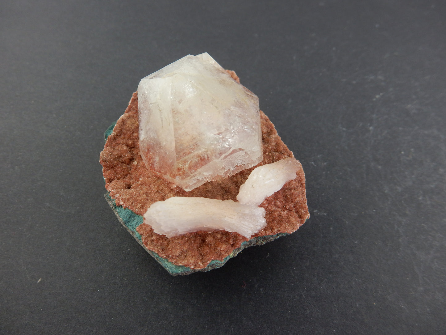 Single gemmy Apophyllite point next to twin Heulandites on a bed of red stilbite?+calcite vug in volcanic matrix
